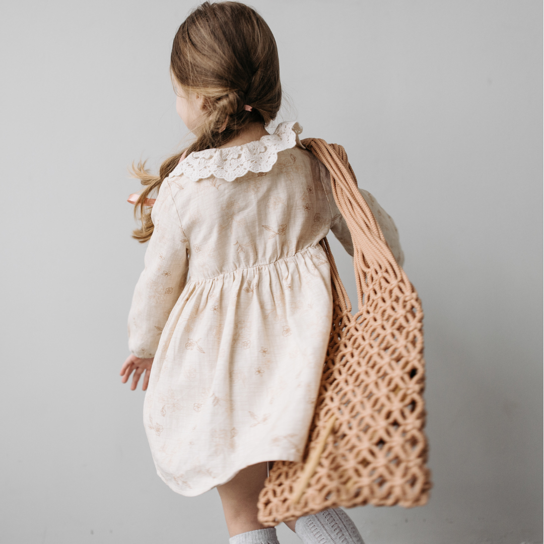 A child holding a handcrafted crochet bag, symbolizing timeless elegance, artisanal craftsmanship, and sustainable fashion with a nostalgic touch.